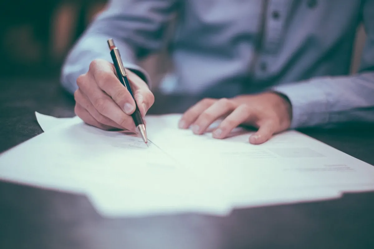 A hand writing notes on paper with a pen